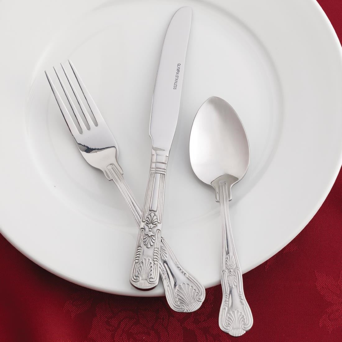 Olympia Kings Dessert Spoon together with fork and knife placed on a plate.