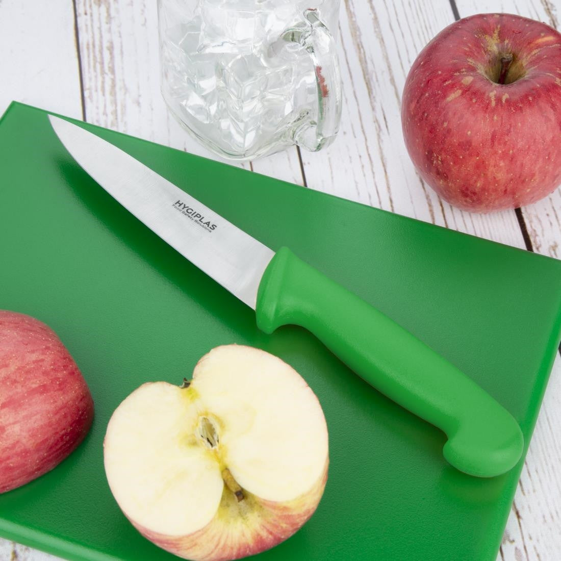 Hygiplas Chef Knife Green 16cm with slice of apple on top of green chopping board.